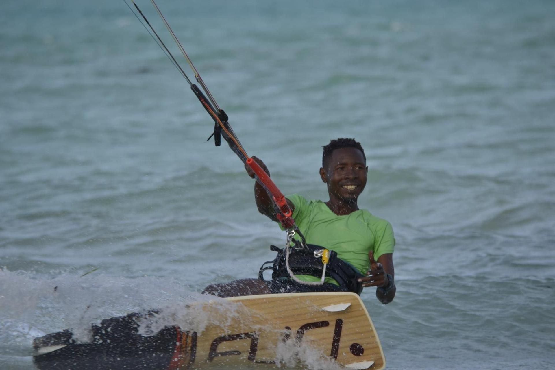 A kitesurfer in a green shirt riding the shallow lagoon off Paje.
