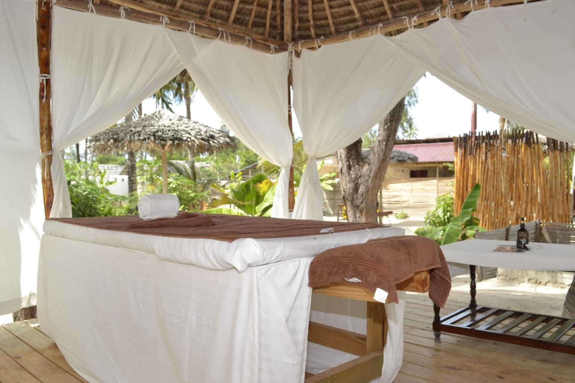 A massage table under white curtains in the open-sided pavilion.