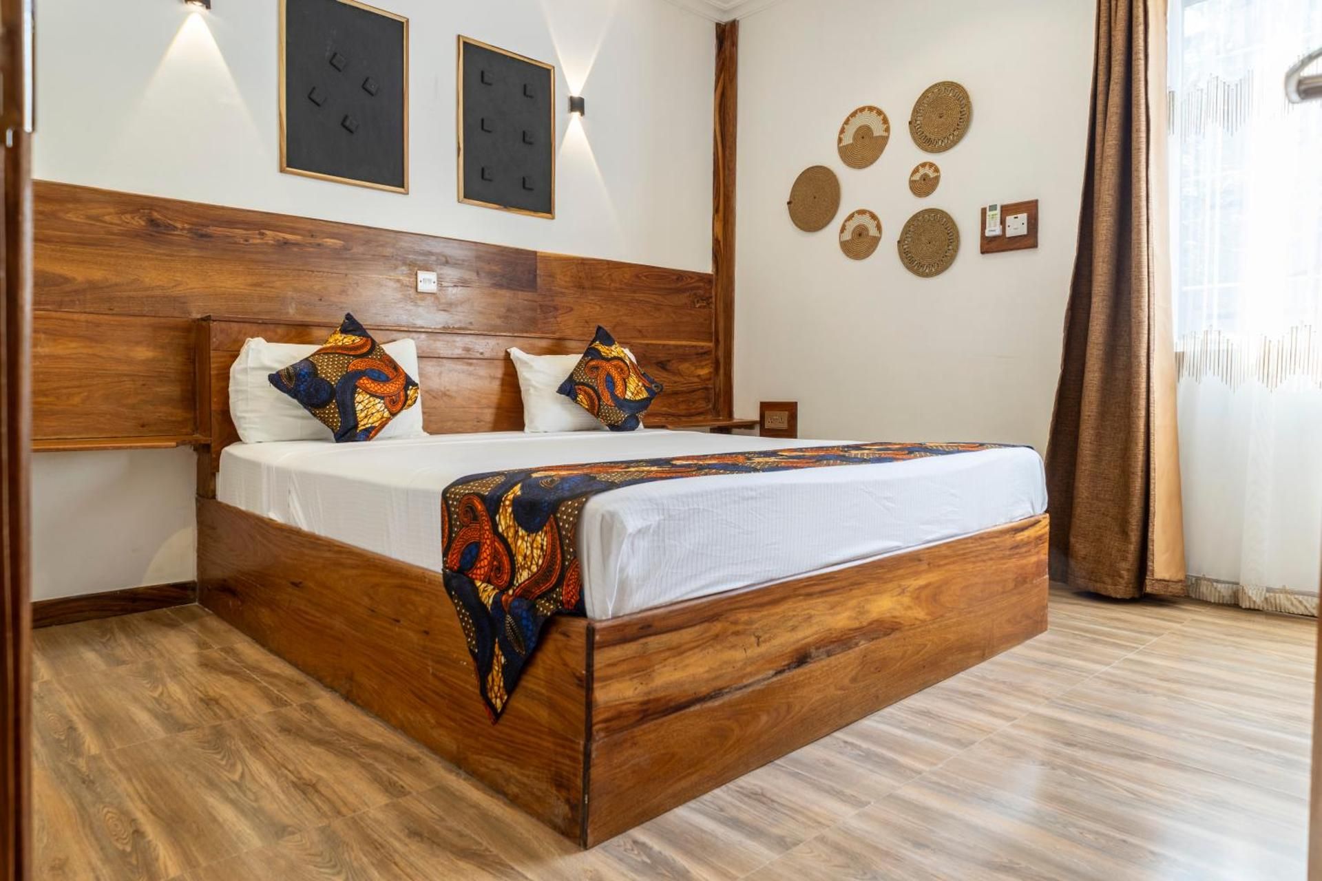 Economy Quadruple Room: a wooden king bed with a printed throw, white walls and woven baskets.