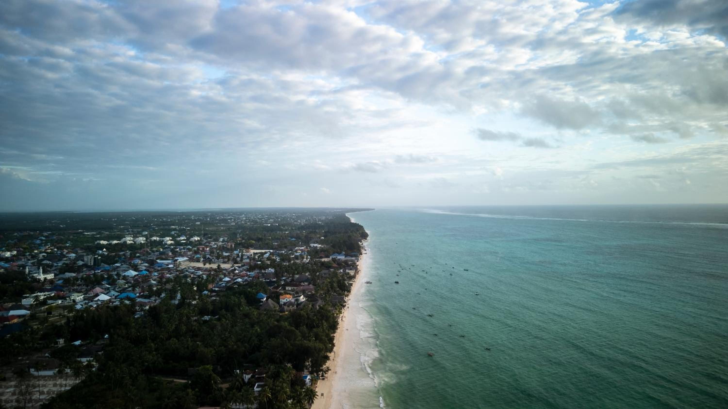 Paje from the air: the village under palms, the long white beach and the turquoise lagoon reaching to the horizon.