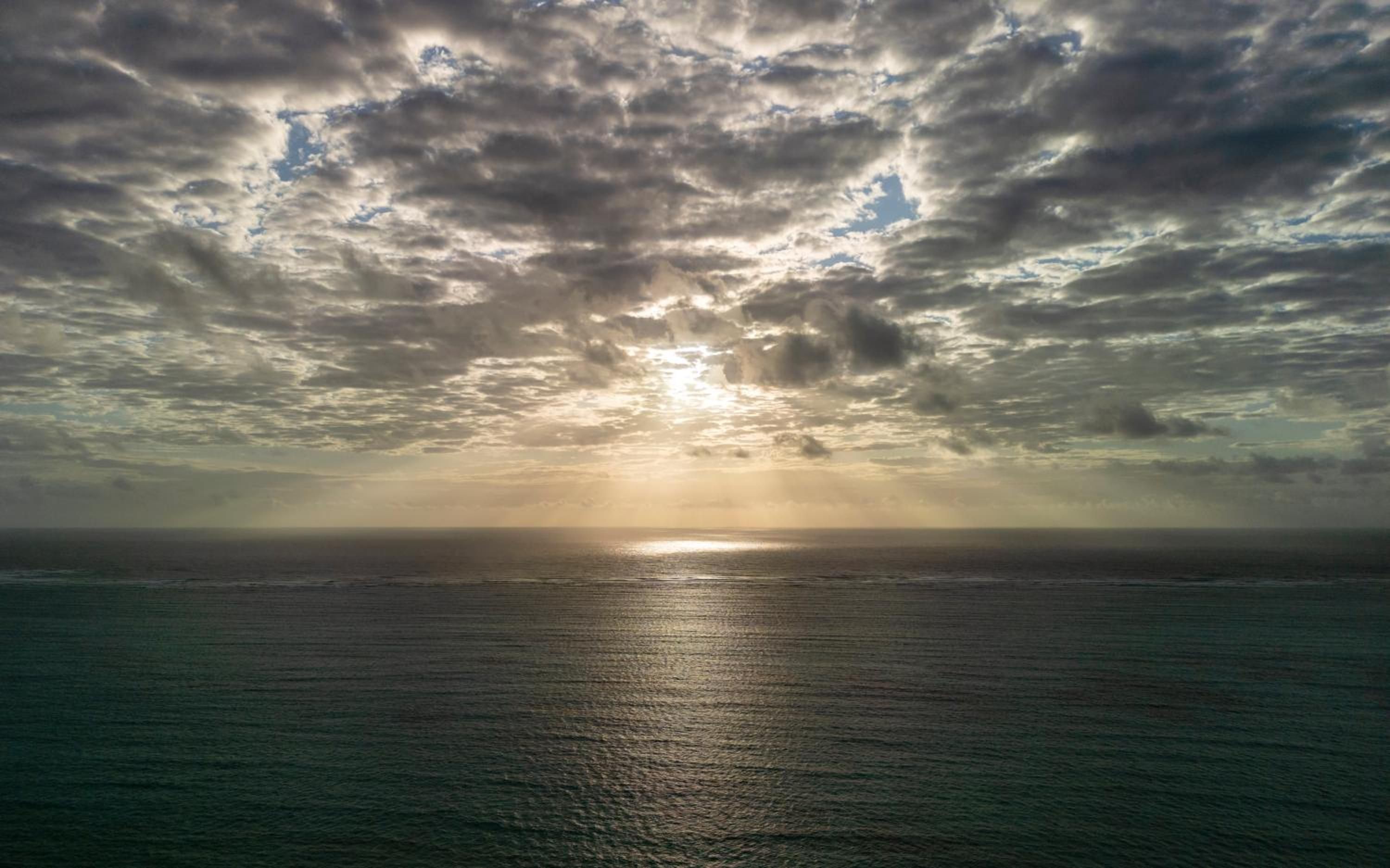 Sunrise over the Indian Ocean off Paje, the light breaking through heavy clouds onto calm water.